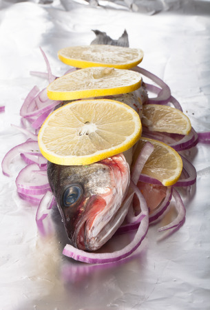Fish prepared for roasting on the foil with lemon and onionの写真素材