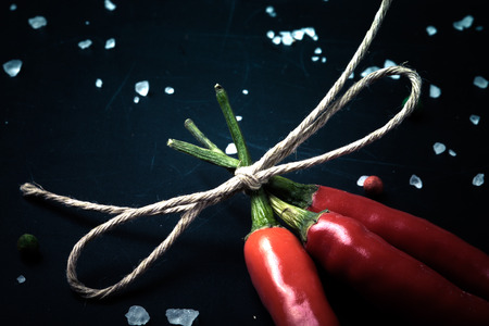 three related twine red hot peppers on a blackboard. With space for text. tintedの写真素材
