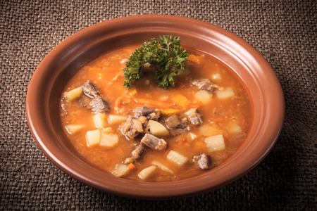 Ceramic plate of vegetable soup standing on sackcloth. tintedの写真素材