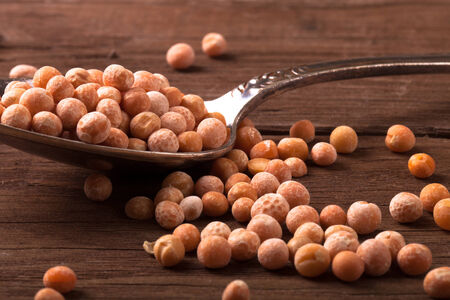 dry peas in a silver spoon on a wooden table. tintedの写真素材