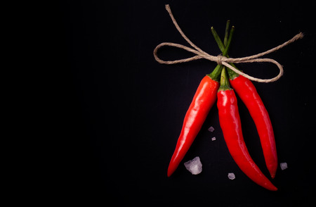 Related hot red chili peppers and a large crystal salt on a dark backgroundの写真素材
