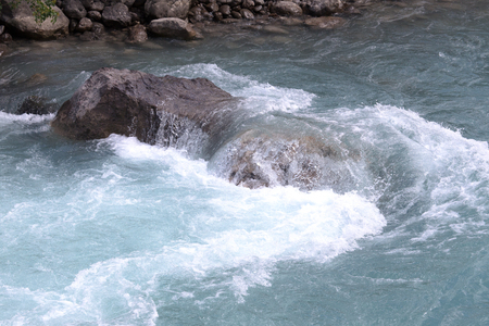 green water of the mountain river and a large stoneの写真素材