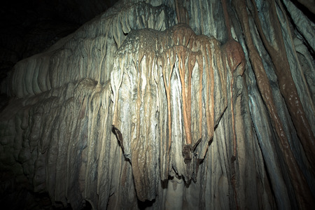 Wall of the cave covered geological formations. tinted
