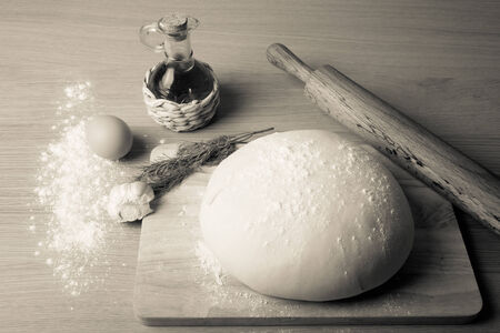 dough on a board with flour. olive oil, eggs, rolling pin, garlic and dill. Tinted.の写真素材