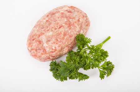 raw meat cutlet with a sprig of parsley on a white backgroundの写真素材