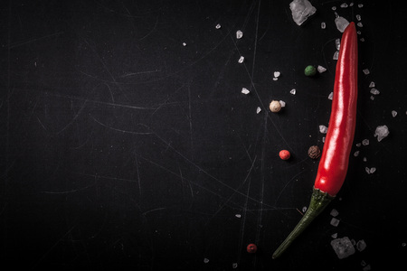 Red hot chilli pepper with sea salt and colored pepper on black background. Toned.の写真素材