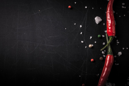 Red hot chilli pepper with sea salt and colored pepper on black background. Toned.の写真素材