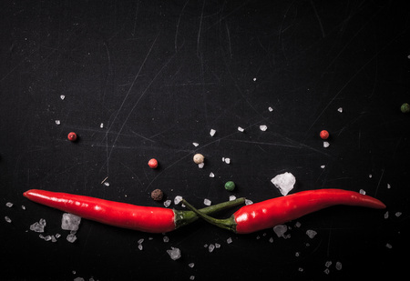 Red hot chilli pepper with sea salt and colored pepper on black background. Toned.の写真素材