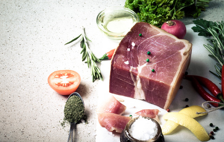 Jamon with herbs and spices, salt, olive oil and tomatoes on stone background. Toned.の写真素材