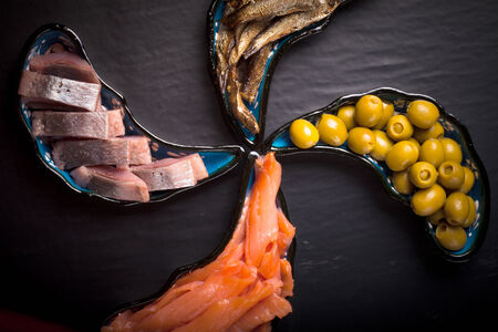 Fish assortment and olives on magic plates on a dark backgroundの写真素材