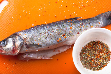 fish and spices on a plastic cutting board. Fish in the process of rubbing spices. tintedの写真素材