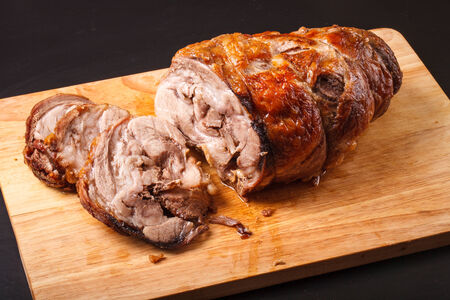 baked pork roll on a wooden board on a dark background.の写真素材