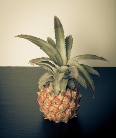 Fresh whole pineapple on a black table near white wall. Toned.の写真素材