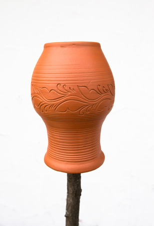 Clay pot with a pattern on a wooden stick on a light background.の写真素材