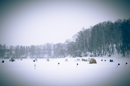 Many flags and tents on the snow-covered field near the forest.の写真素材