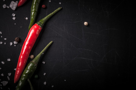 Red and green hot chilli pepper with sea salt and colored pepper on black background. Toned.の写真素材
