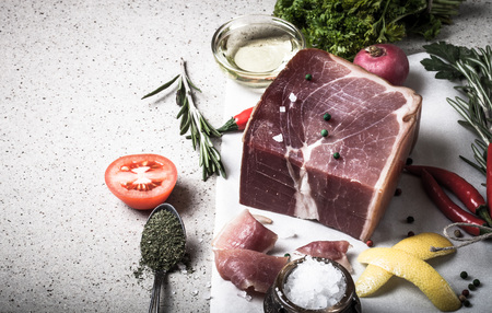 Jamon with herbs and spices, salt, olive oil and tomatoes on stone background. Toned.の写真素材