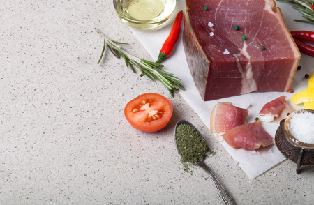 Jamon with herbs and spices, salt, olive oil and tomatoes on stone background.の写真素材