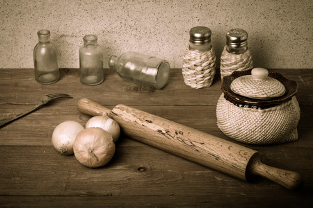 Onion, salt, pepper, rolling pin, old bottles and fork on the old wooden table. Toned.の写真素材