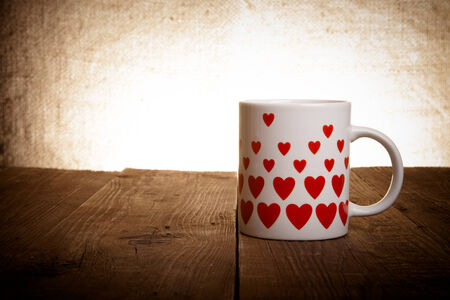 Mug with many pictured hearts on the old wooden table. Toned.の写真素材