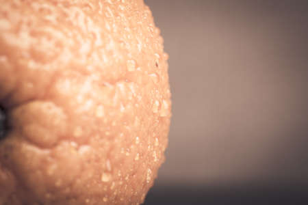 Orange with water drops on the skin close-up on a light background. Shallow depth of field. Toned.の写真素材