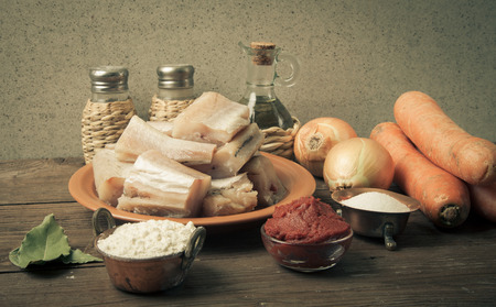 Pieces of fresh fish on a plate, vegetables, flour, tomatoe paste and spices on a wooden board. Toned.の写真素材