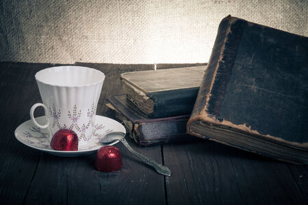 Cup of coffee, shokolad and stack of old books on the old wooden table. Toned.の写真素材