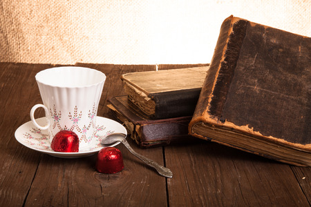 Cup of coffee, shokolad and stack of old books on the old wooden table.の写真素材