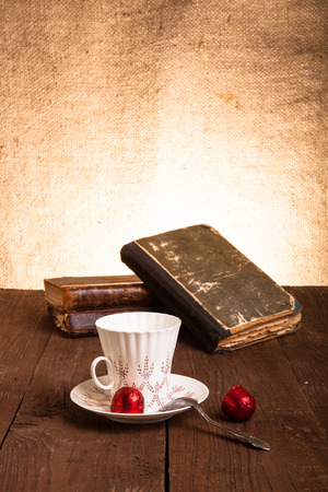 Cup of coffee, shokolad and stack of old books on the old wooden table.の写真素材