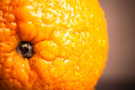 Orange with water drops on the skin close-up on a light background. Shallow depth of field. Toned.の写真素材