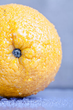 Orange with water drops on the skin close-up on a light background. Shallow depth of field. Toned.の写真素材