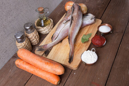Still life with fish, vegetables and spices on a wooden board.の写真素材