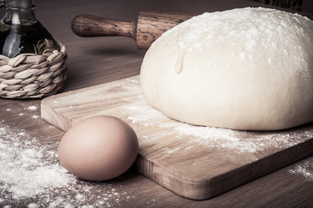 dough on a board with flour. olive oil, eggs, rolling pinの写真素材