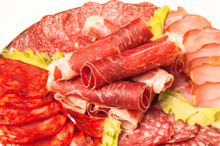 Slices of different kinds of meat with green salad.の写真素材