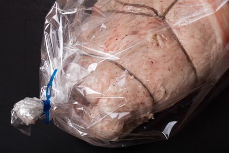 Raw meat with rope in the package on a black background.の写真素材