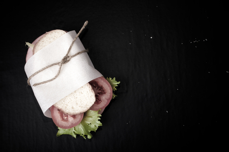 sandwich with sausage bandaged twine on a black background.の写真素材