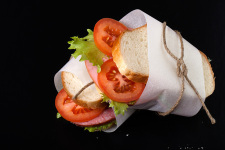 sandwich with sausage bandaged twine on a black background.の写真素材