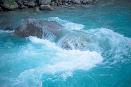 green water of the mountain river and a large stoneの写真素材