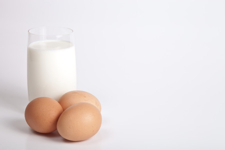Glass of milk and three eggs on a light background.の写真素材