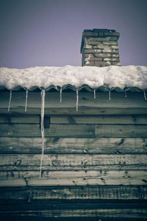 Brick chimney on the snow-covered roof of a wooden house. の写真素材