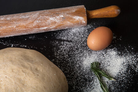 Flour, rolling pin, egg, rosemarin and dough for pie.