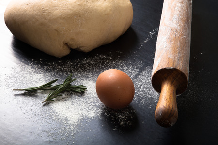 Flour, rolling pin, egg, rosemarin and dough for pie.の写真素材