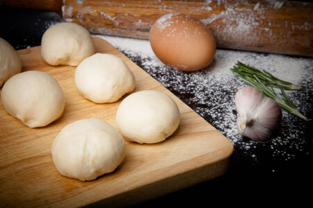 dough on a board with flour. olive oil, eggs, rolling pin, garlicの写真素材