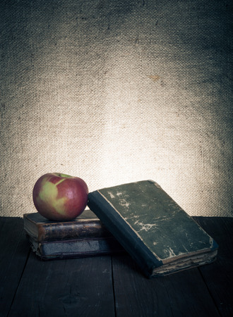 Still life with apple and a stack of old books on old wooden table. Tonedの写真素材