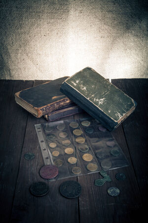 Vintage books and coins on old wooden table. Toned.の写真素材