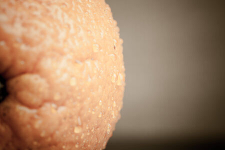 Orange with water drops on the skin close-up on a light background. Shallow depth of field. Toned.の写真素材