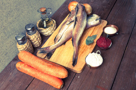Still life with fish, vegetables and spices on a wooden board. Toned.の写真素材