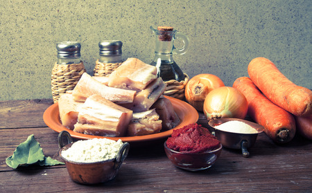 Pieces of fresh fish on a plate, vegetables, flour, tomatoe paste and spices on a wooden board. Toned.の写真素材