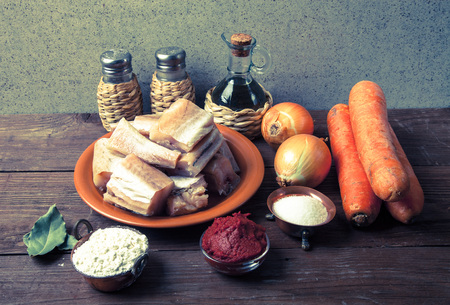 Pieces of fresh fish on a plate, vegetables, flour, tomatoe paste and spices on a wooden board. Toned.の写真素材