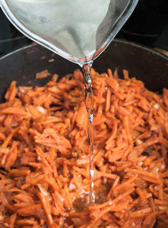 Frying pan with fried carrots. Water flowing.の写真素材